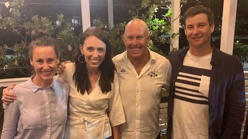 Two women and two men pose for a photo in a restaurant.