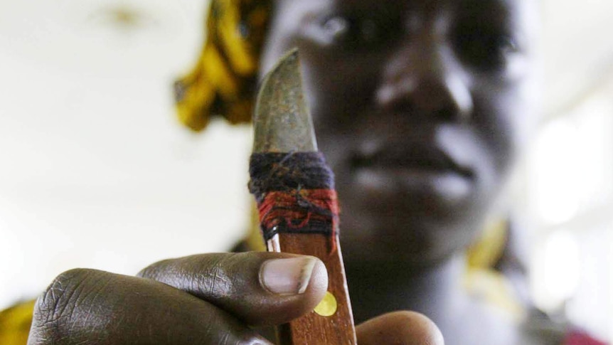 A woman who performs genital cutting holds the knife