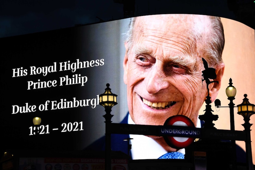Prince Philip smiles in a picture on the screen at Piccadilly Circus in London with text with his name and birth and death date.