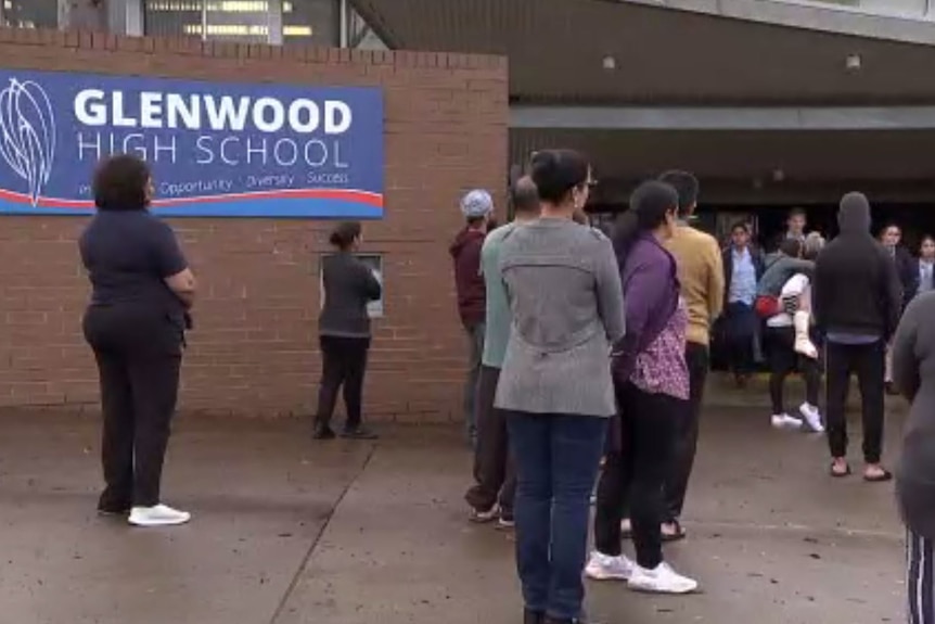 Parents stand outside a school