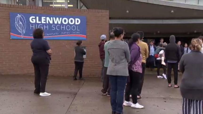 Parents stand outside a school