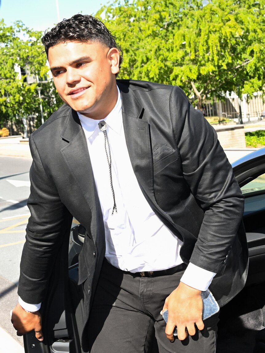 Latrell Mitchell wearing a black suit steps out of a car. 
