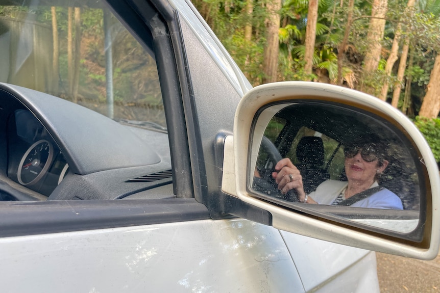 A woman's reflection in a car's side mirror. 