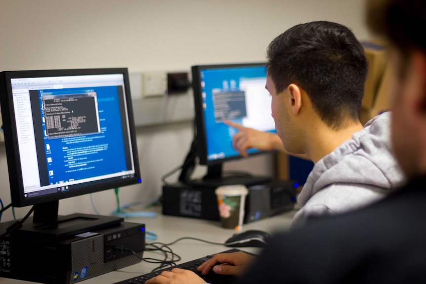 A student in a grey hoodie stares at a computer screen during class.