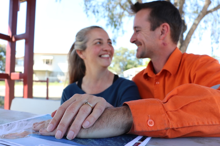 Engaged couple Kerri Brown and Brett Halford, smiling at each as they sit in a park at Ipswich, west of Brisbane