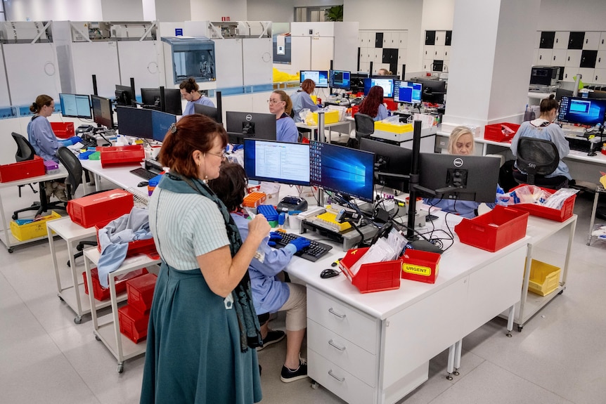 A science lab at Sullivan Nicolaides Pathology, filled with scientists looking at computers