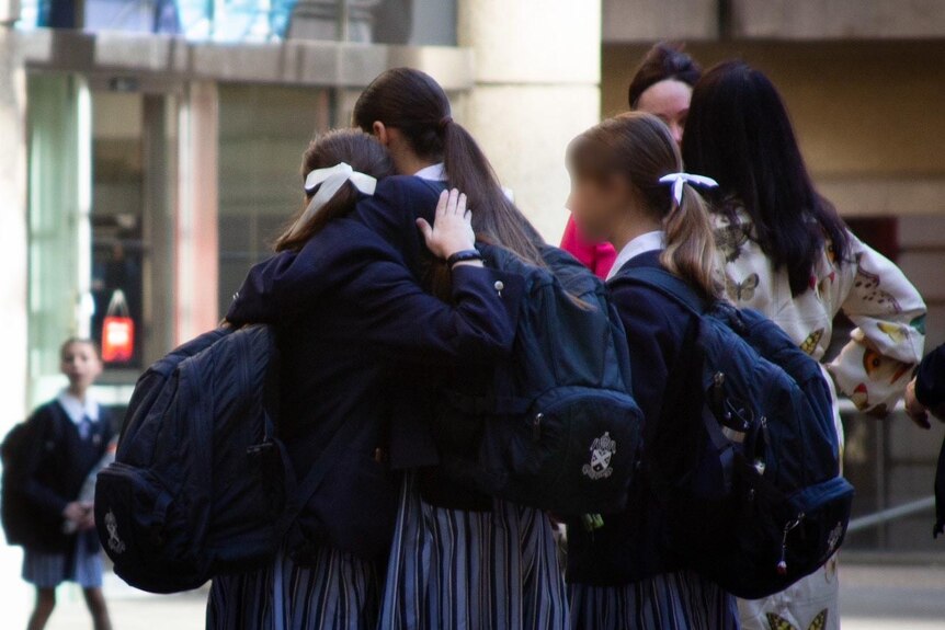 School students hug outside of St Andrew's Cathedral School in Sydney