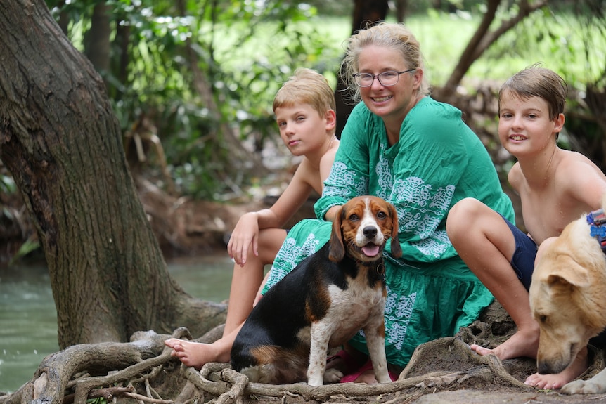 Family posing beside dramatic tree roots along a scenic shady creek.