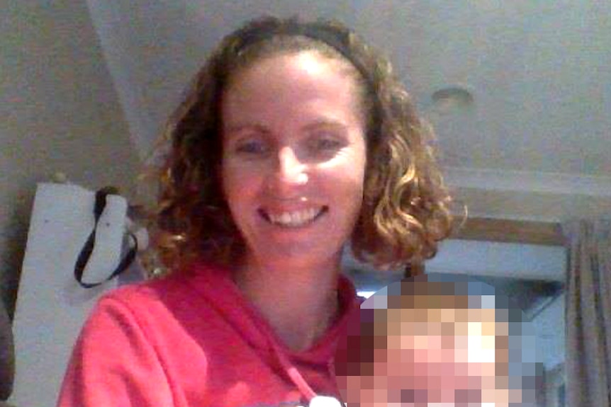 Amanda Harris is pictured holding a baby whose face has been blurred.