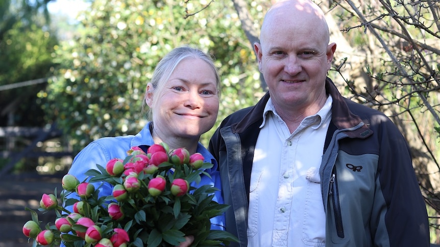 Tanya and Mark Beech holding a bunch of freshly picked peonies.
