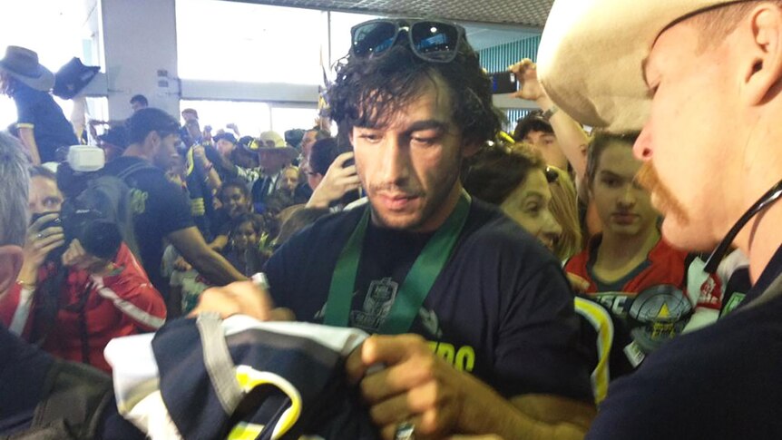 Thurston adds an autograph to a Cowboys jumper for a fan in Townsville