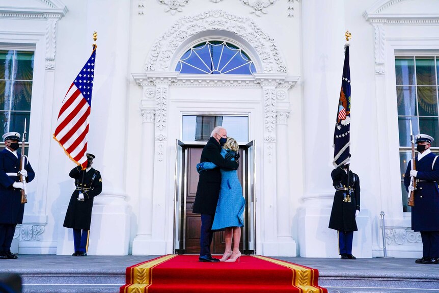 Joe Biden hugging Jill Biden outside the White House doors flanked by US Marines