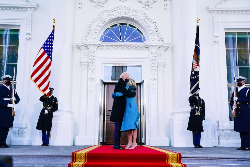 Joe Biden hugging Jill Biden outside the White House doors flanked by US Marines