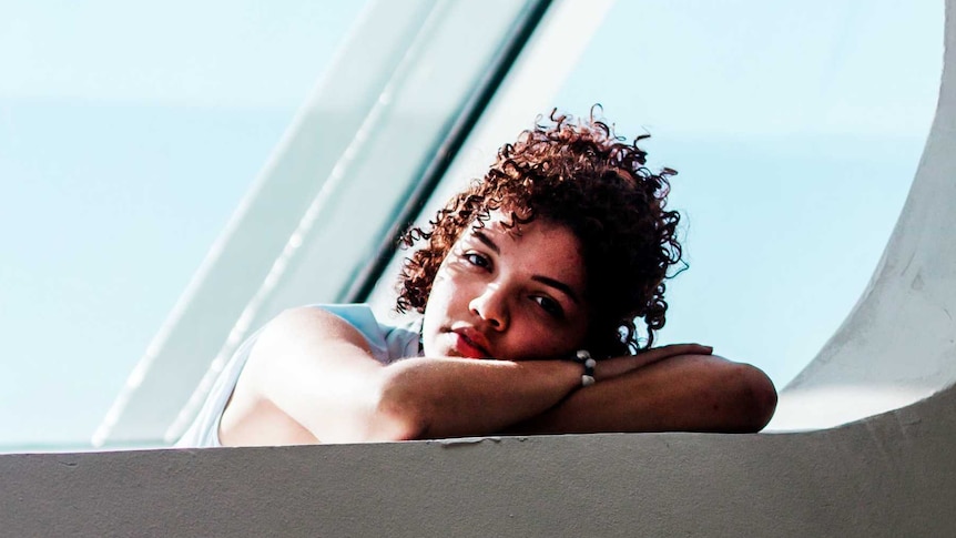 Woman with head resting on arms looking towards camera