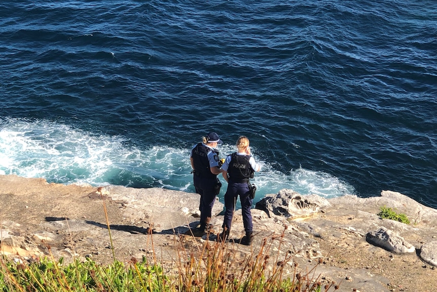 Two police officers stand on a headland. 