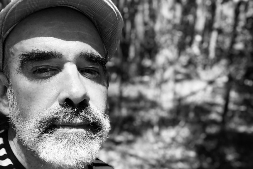 Marriage celebrant Sean M Whelan photographed in a bush setting wearing a striped t shirt and cap, has been single for 4 years.