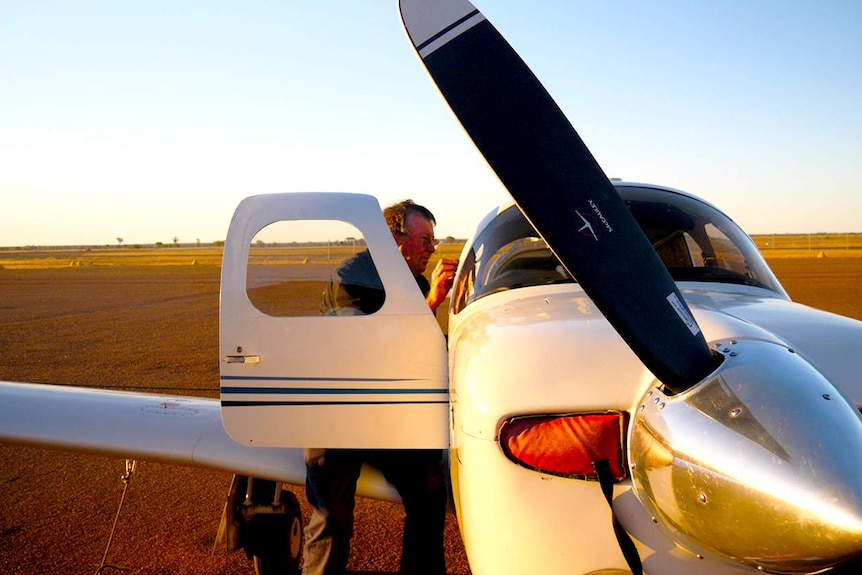 A man looking inside of a white light aircraft