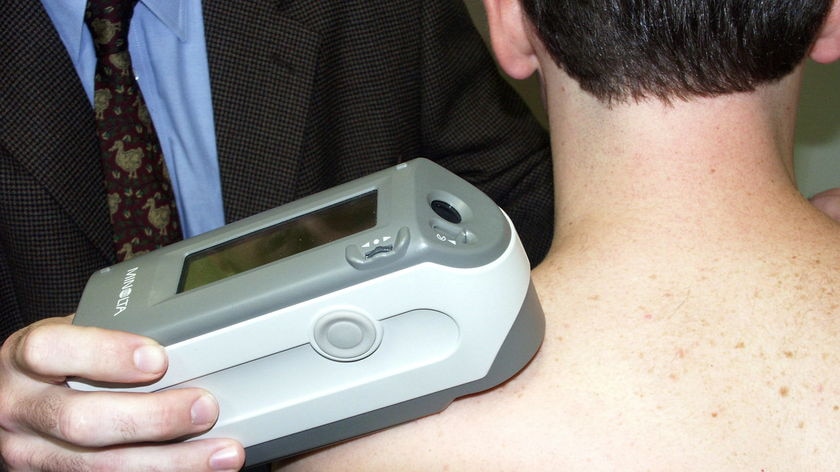 A skin cancer doctor uses a spectrophotometer to detect pigment changes on the skin of a patient.