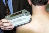 A skin cancer doctor uses a spectrophotometer to detect pigment changes on the skin of a patient.