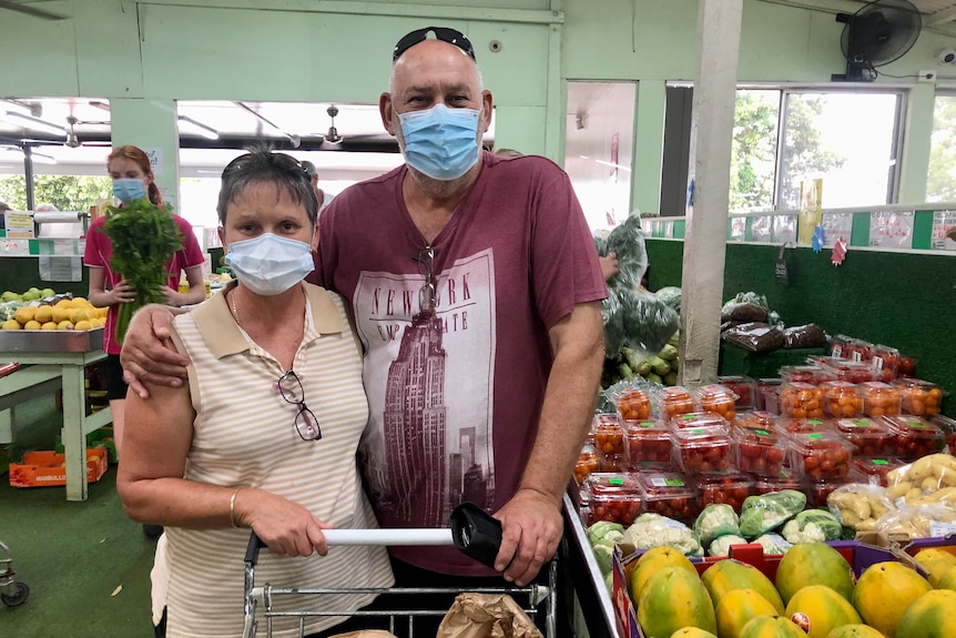 Two shoppers stand in front of shopping cart with fresh fruit and vegetables next to them