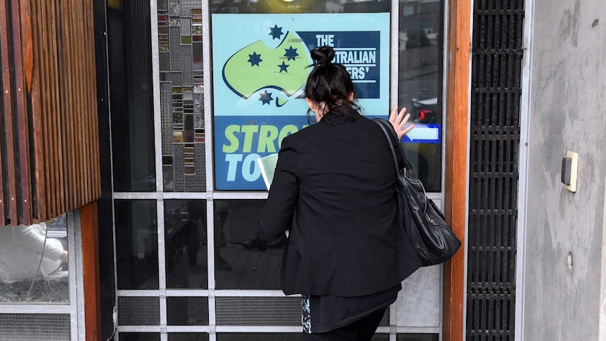 A woman wearing a black blazer walks into the AWU building