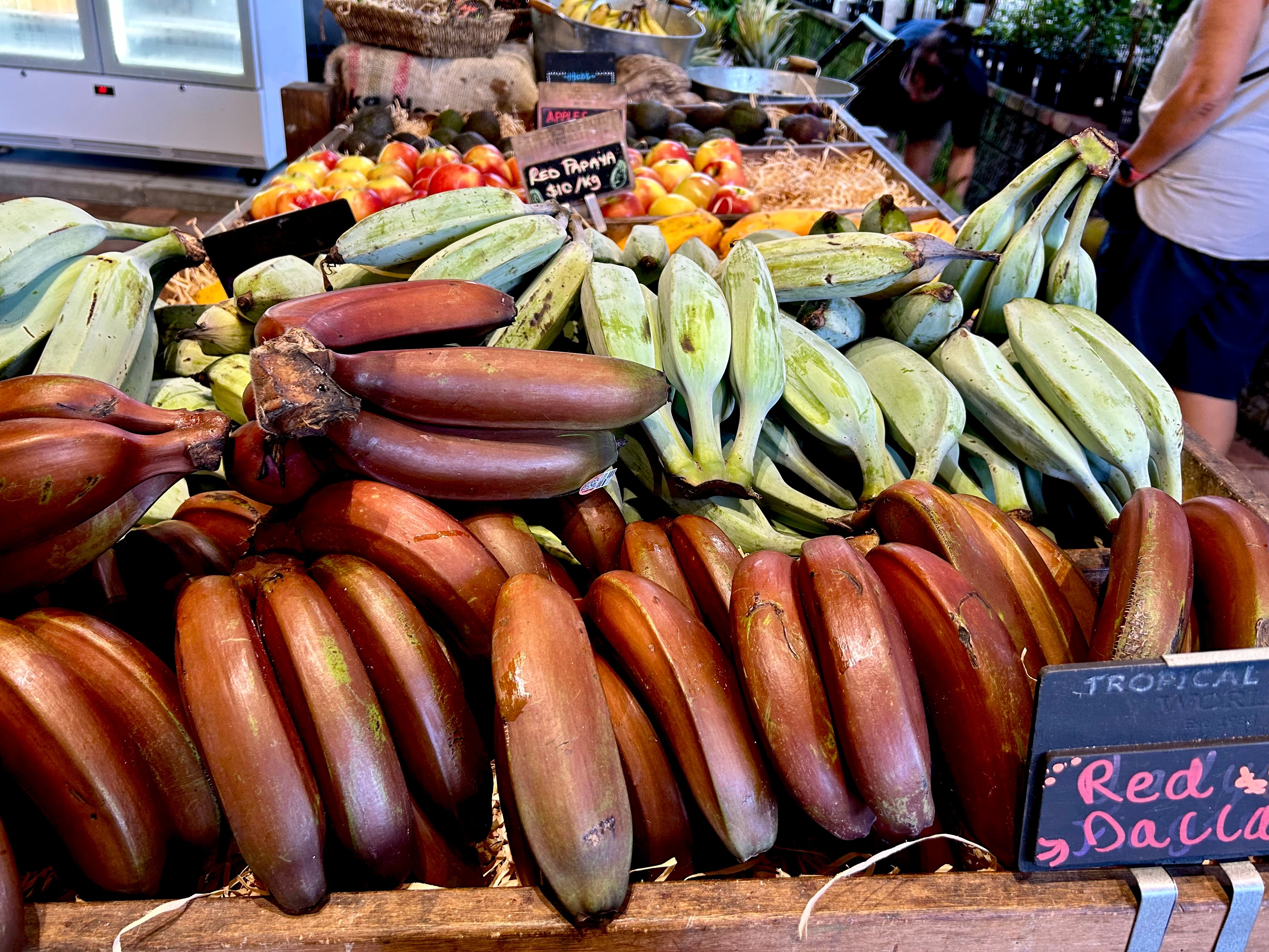 Hands of red and green bananas for sale.