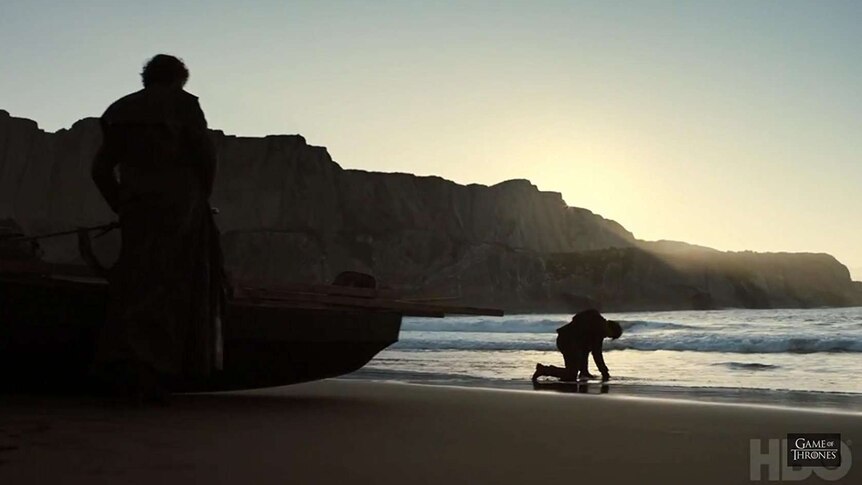 Theon Greyjoy bent over in the sand of a beach, recovering from a fight.
