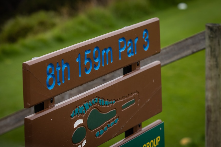 A wooden sign on a fence that says "8th 159m Par 3"