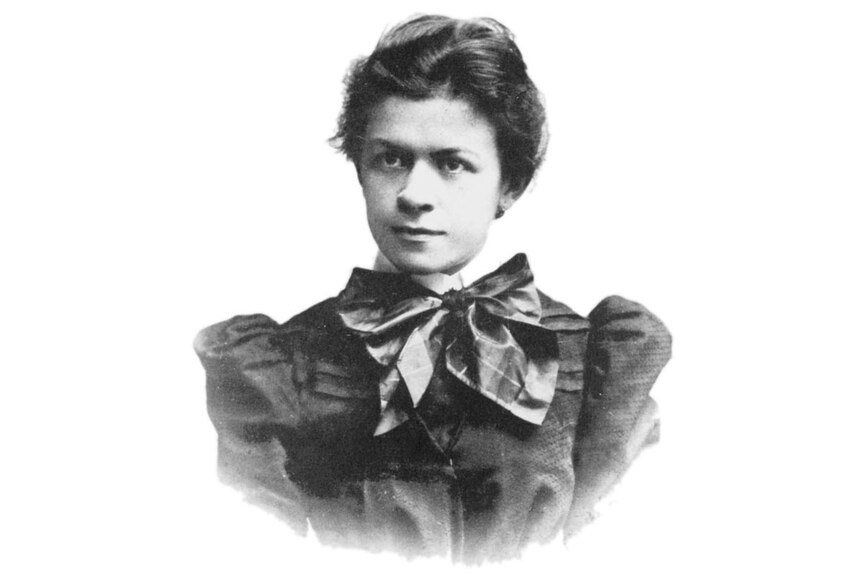 Black and white photo of young woman in black dress with swept-up hair.