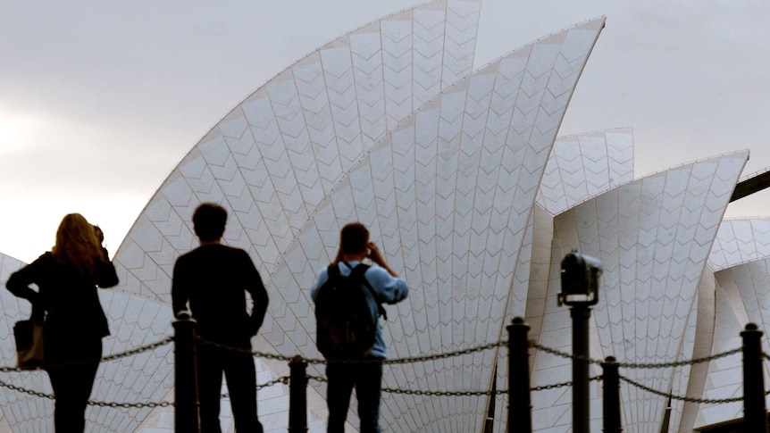 Tourists take photographs and video of the Sydney Opera House from a lookout on the headland known as Mrs Maquarie's Chair.