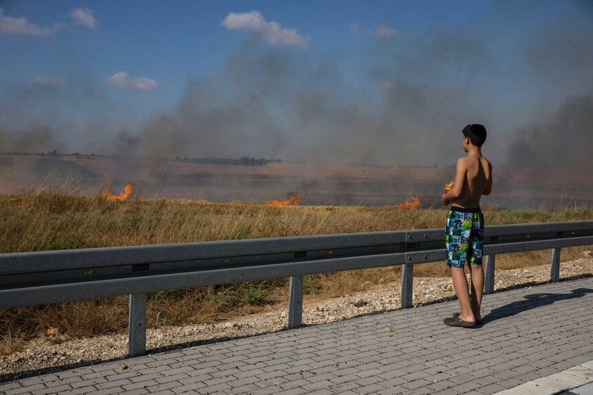 Israeli watches a fire started by a kite with attached burning cloth launched from Gaza.