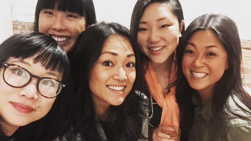Ra Chapman is surrounded by a group of smiling women, all Korean-Australian adoptees