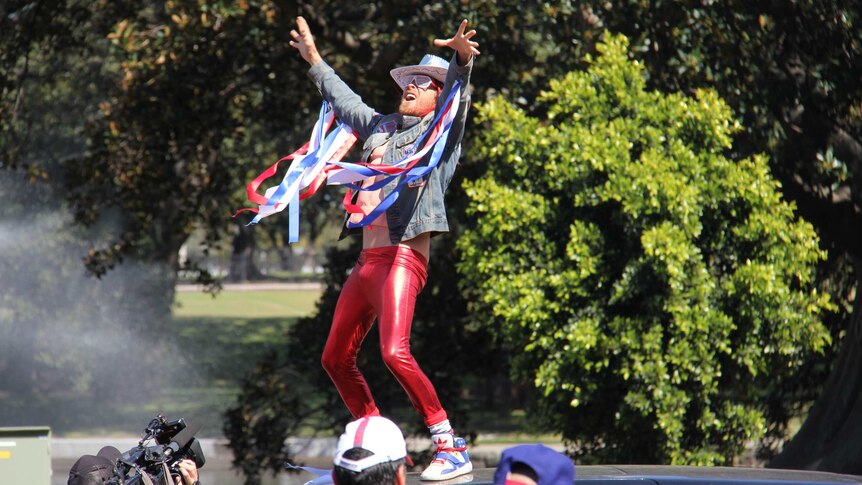 A Roosters supporter on top of a Tarago