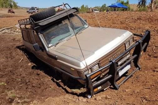 A 4WD bogged in mud up to its bumper bar.