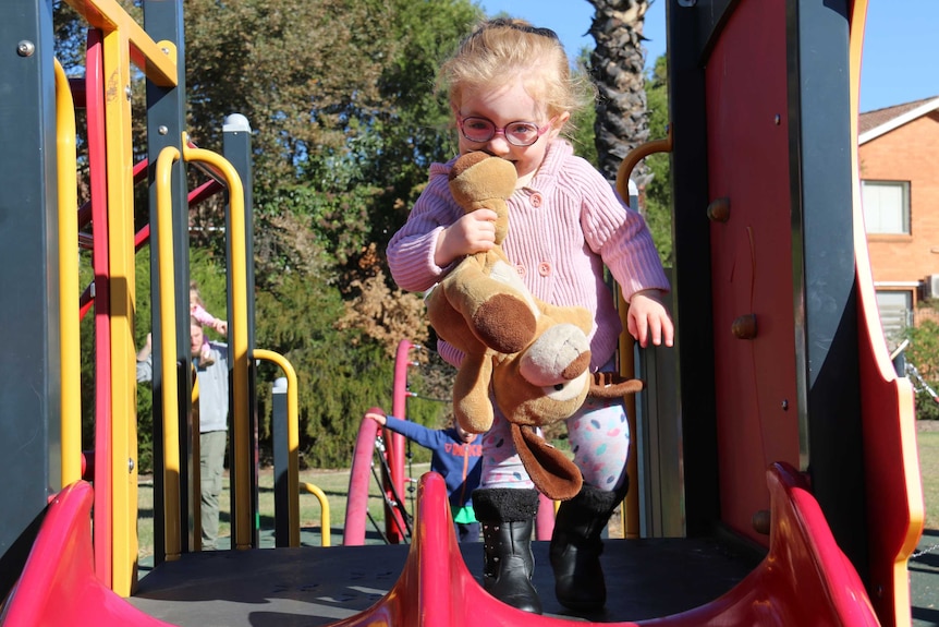 A little girl on play equipment.