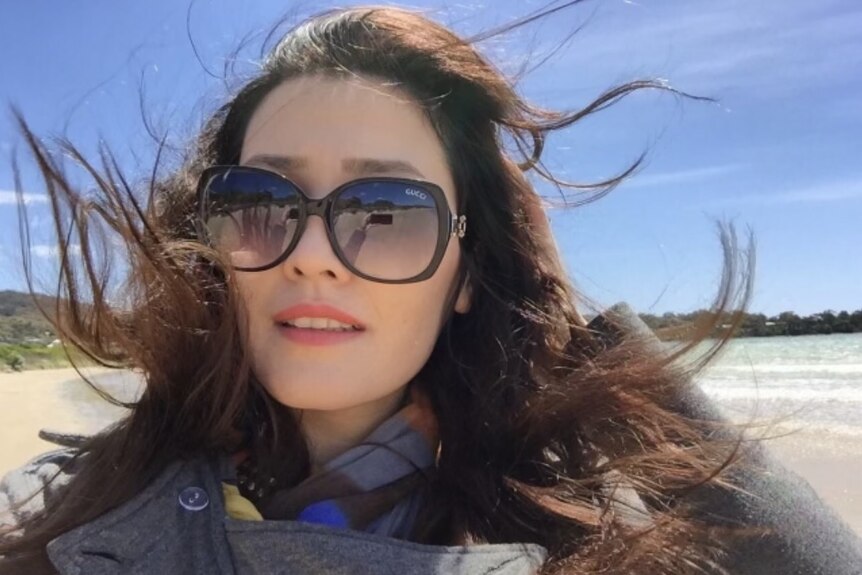 A photo of a woman in sunglasses and wind in her hair. 