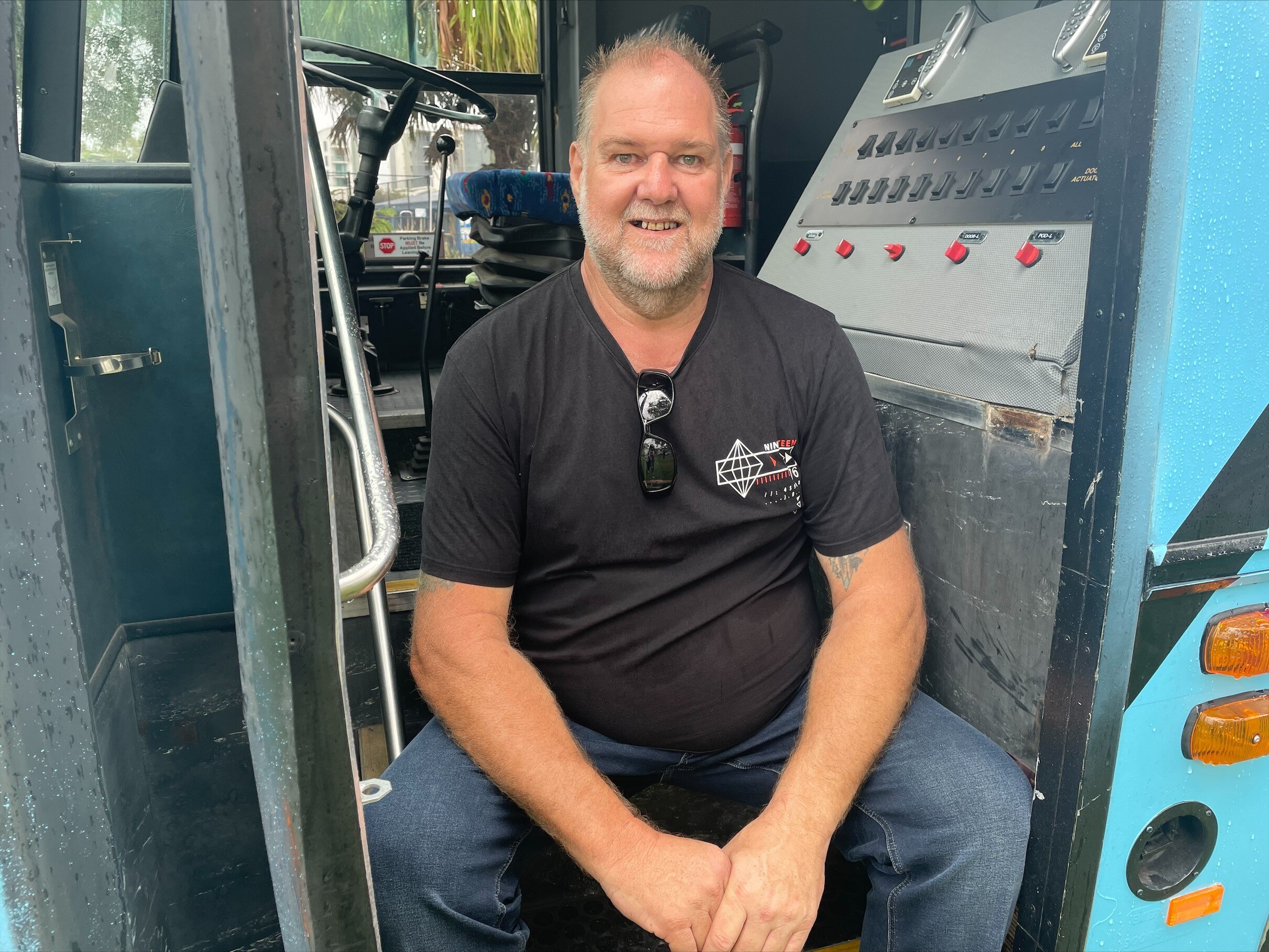Man smiling, sitting inside door of bus