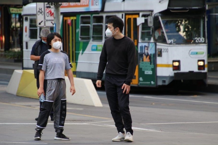 A man and child in a Melbourne street with a tram behind them.
