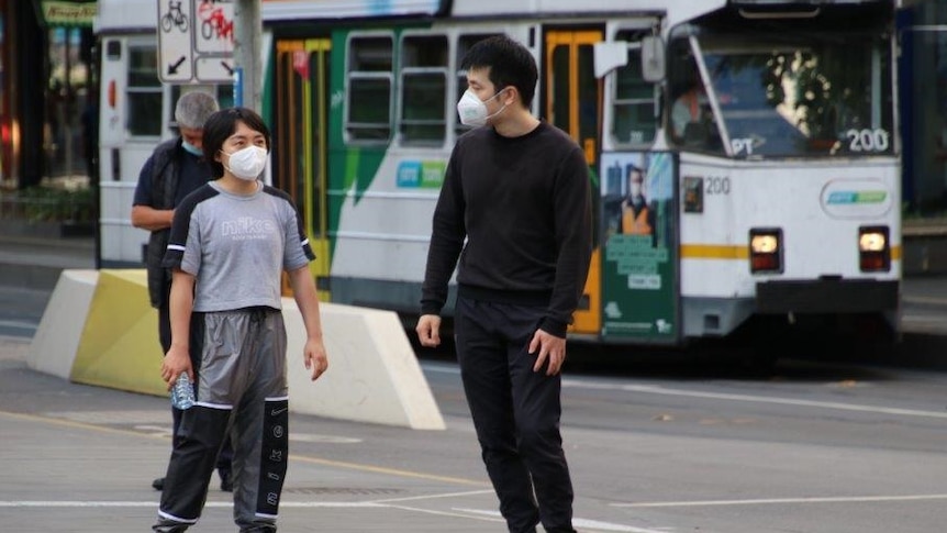 A man and child in a Melbourne street with a tram behind them.