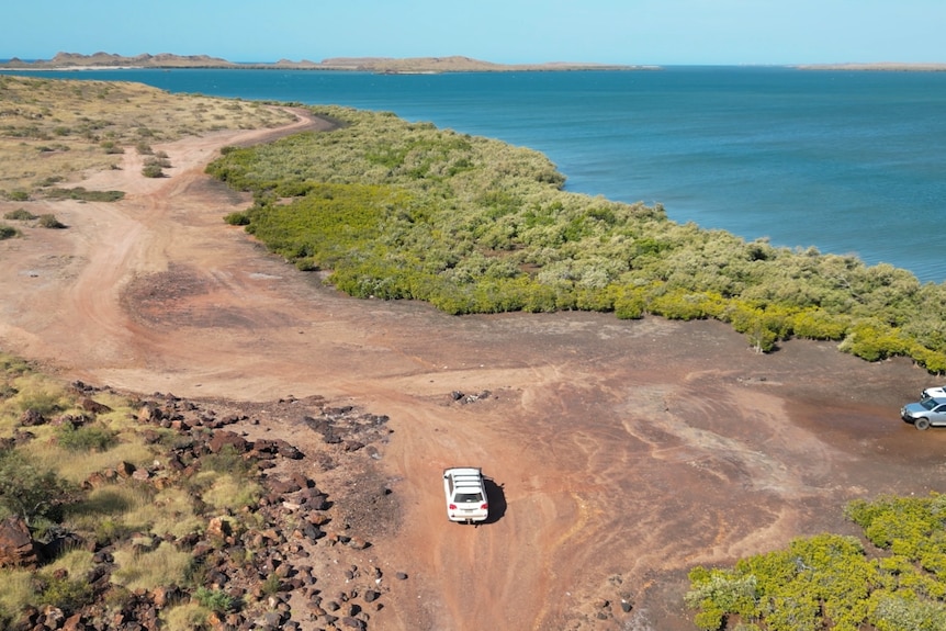 Four wheel drive on red dirt with blue ocean in background