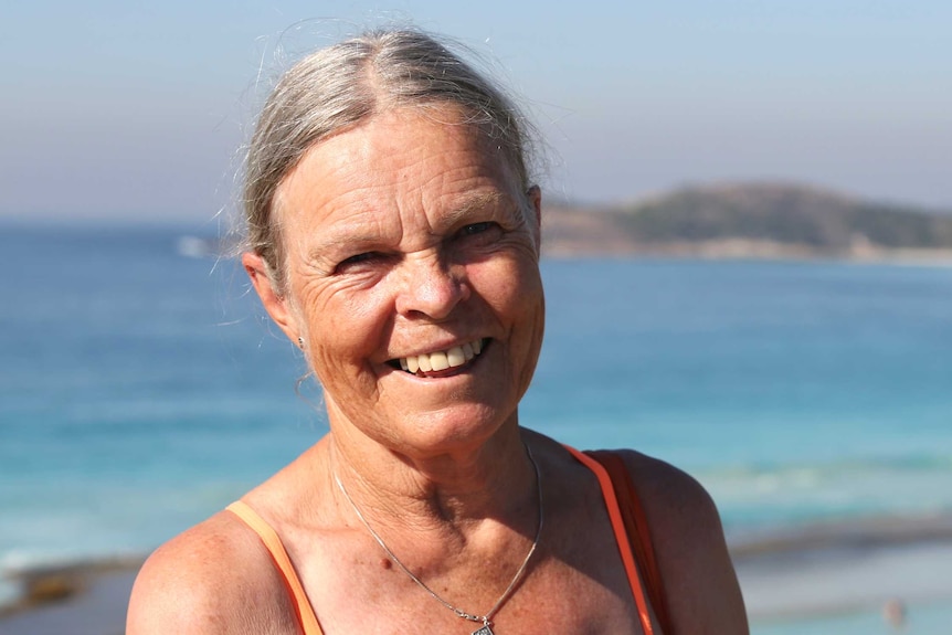 An older woman in a swimsuit at the beach.