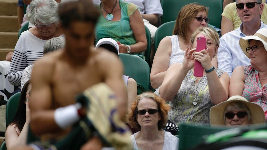 A spectator takes a photograph of Rafael Nadal as he changes his shirt at Wimbledon.