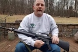 Man sits and holds rifle