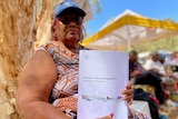 An aboriginal woman holding a paper copy of the Aboriginal Cultural Heritage Bill 
