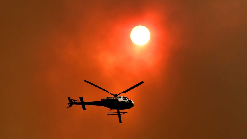 A helicopter silhouetted against a smoky sky.