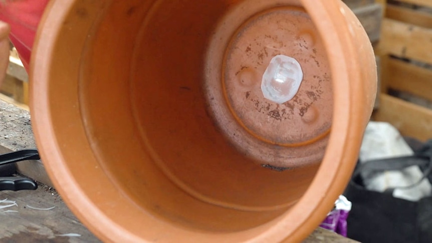 Large plastic pot with hole at base covered with plastic.