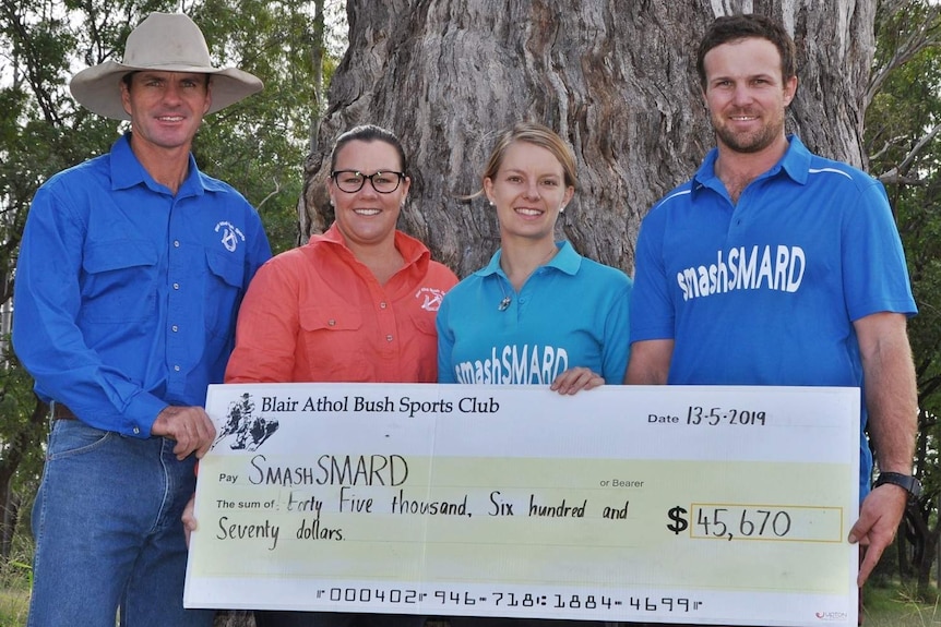 Four people stand in a line and hold up an oversized cheque for $45,670.