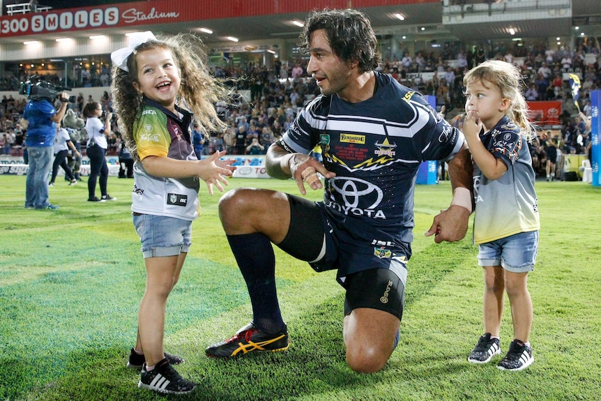 Johnathan Thurston kneeling with his children before the Cowboys versus Sharks NRL match in Townsville.