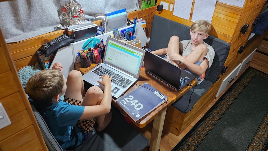 Two boys sitting a table on laptop doing school work