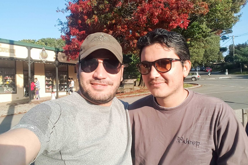 Samar and Zalman stand in front of a tree and shops